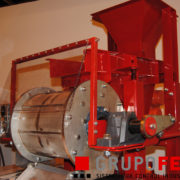 Vibrating feeder between a hopper and a rotary drum